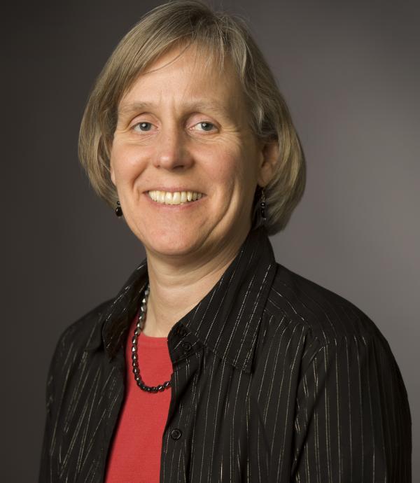 a person in red shirt and black collared blouse smiling at the camera