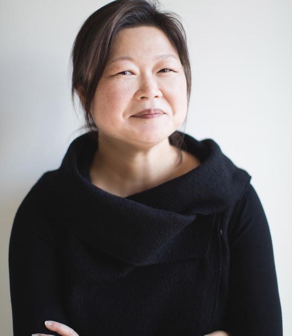 a person in a black blouse looking at the camera against a white background