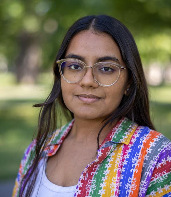 Person wearing glasses and colorful striped sweater over white undershirt
